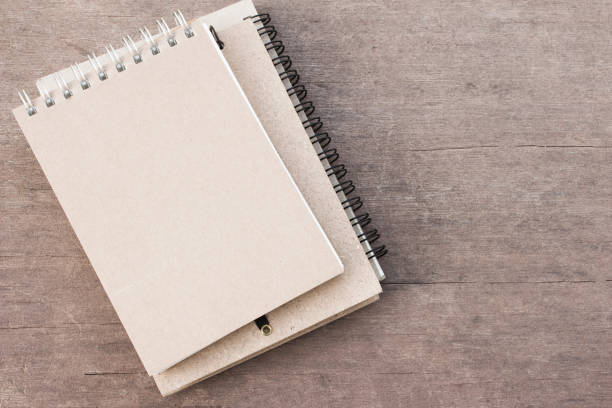istock blank brown book, white notebook on old wood table background 970717768