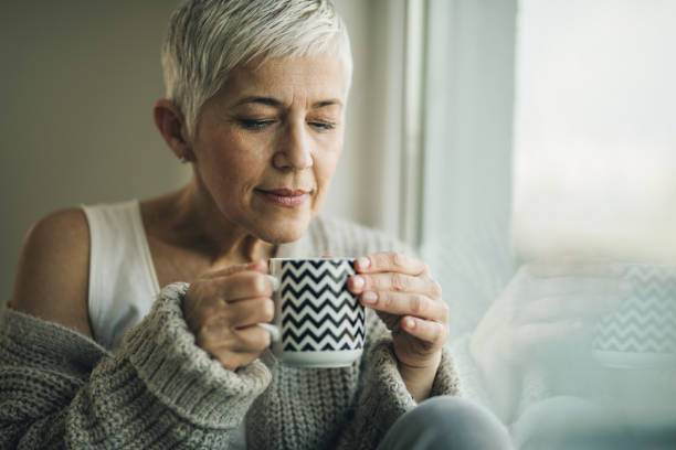 istock Mature woman smelling her coffee while relaxing by the window. 970718948