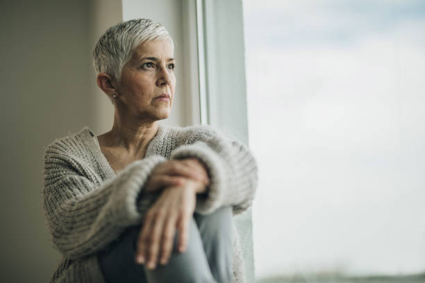 istock Senior woman looking through the window and thinking about something. 970730140