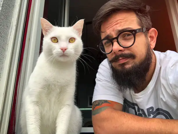 Photo of Man With White Cat On The Window