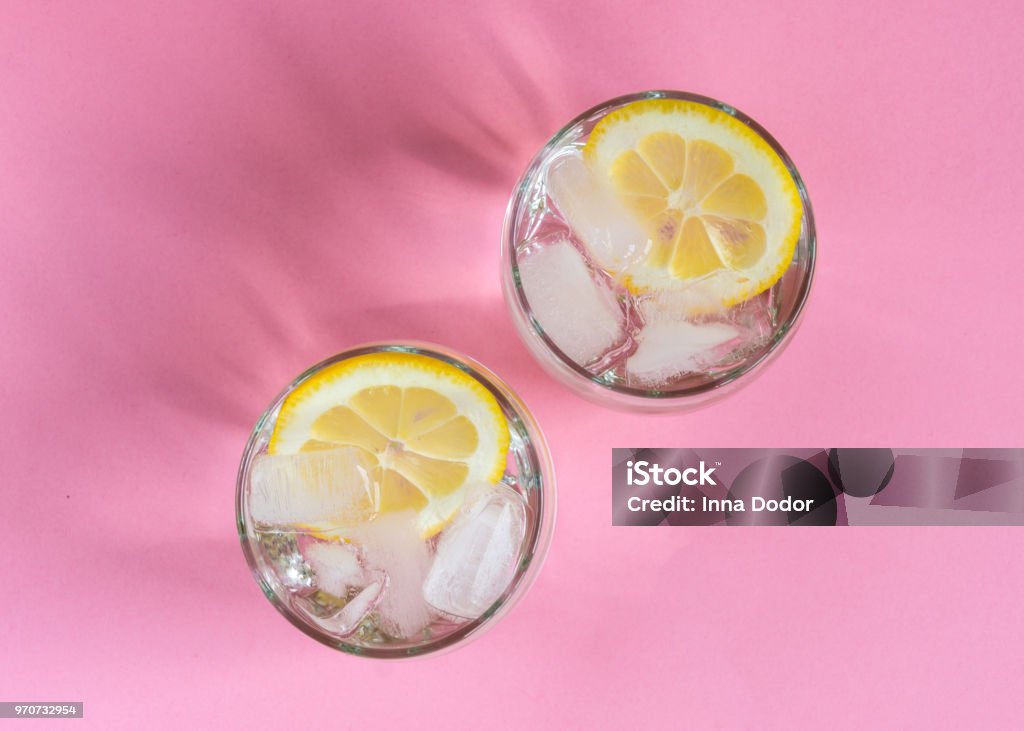 Deux verres de l’eau froide avec des tranches de citron et glace sur fond de couleur pastel. - Photo de Citron libre de droits