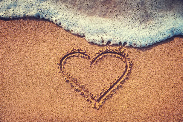 istock Drawing heart on the sand. Summer love background. 970736454