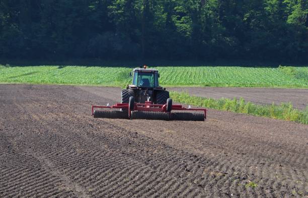 istock Tractor with a towing roller compactor makes the surface of the plowed field uniform 970736694