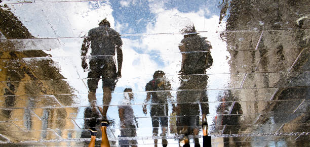 sagome di riflessione sfocate di persone che camminano in una giornata piovosa - reflection on the water foto e immagini stock