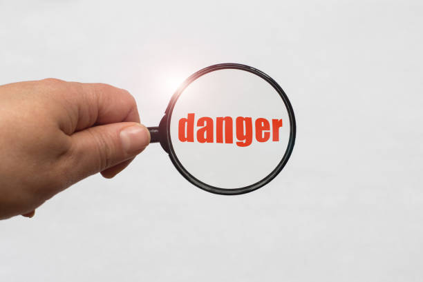istock magnifying glass in hand and a danger word on the white background 970739462