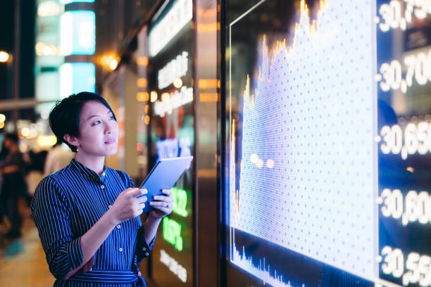 le imprenditrici asiatiche controllano i dati del mercato azionario su tablet prima della scheda di visualizzazione finanziaria di hong kong - stock market stock exchange city global finance foto e immagini stock