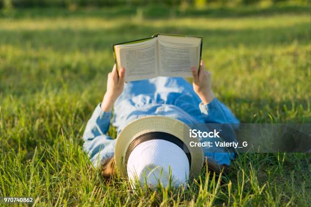 Ragazza In Abito E Cappello Giace Su Un Libro Di Lettura In Erba Verde Vista Dallalto - Fotografie stock e altre immagini di Leggere