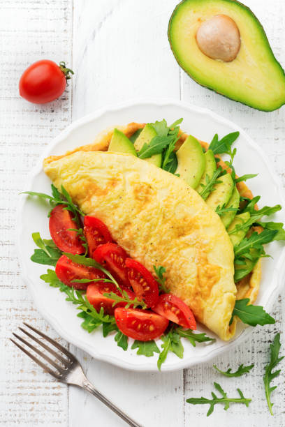 istock Omelette with avocado, tomatoes and arugula on white ceramic plate on light stone background. Healthy breakfast. Selective focus. Top view. Copy space. 970753008