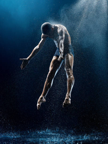 Athletic ballet dancer performing with water Athletic afro american ballet dancer dancing with water drops over blue background. Aqua, spray, splash, rain concept. Modern contemporary choreography with young professional man ballet photos stock pictures, royalty-free photos & images