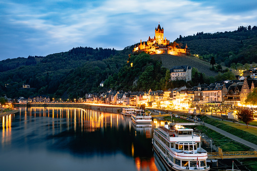 Beautiful city view of historic old town Cochem illuminated at dusk time like a postcard with the typical half-timbered colorful houses, hotels and restaurants, Reichsburg Imperial castle landmark on a mountain, Mittelmosel, Moselle river, Rhineland-Palatinate in spring time Rheinland-Pfalz Deutschland, Europe