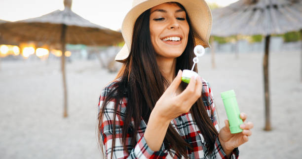 istock Happy young woman blowing bubbles on the beach 970763152