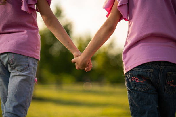 istock Close up twin sisters holding hands 970775584