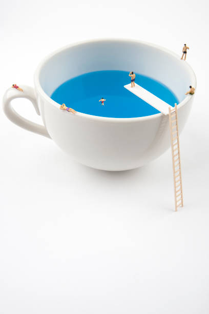istock miniature people in mug cup swimming pool 970775732