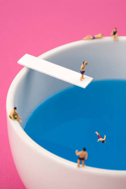 miniature people in mug cup swimming pool.