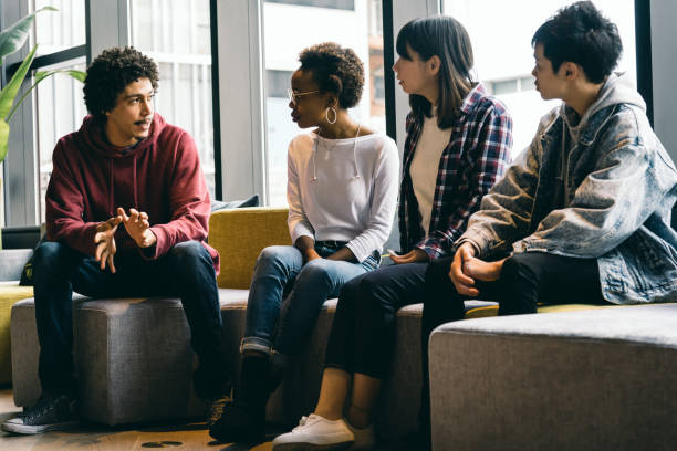 hombres y mujeres jóvenes están hablando en una sala de reuniones - liderazgo juvenil fotografías e imágenes de stock