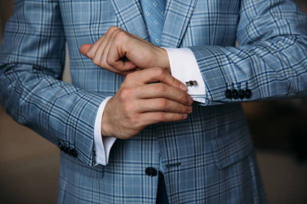 le mani dello sposo ravvicinato tengono i gemelli. elegante gentleman clother, camicia bianca e cintura nera. concetto di abiti da lavoro classici in ufficio, gioielli - cuff link suit men wedding foto e immagini stock