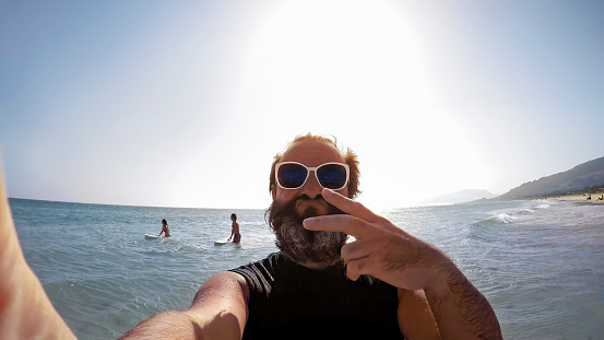 Mature man taking a selfie on beach.