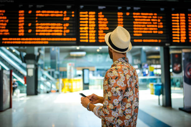 Tourist man looking at the timetable board. Tourist man with the hat looking at the timetable board cancelled stock pictures, royalty-free photos & images