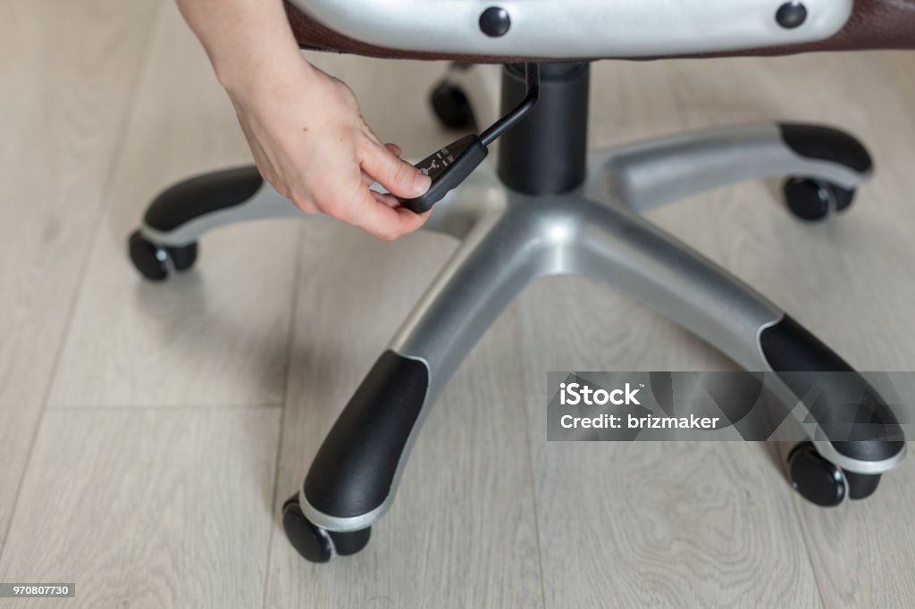 Het meisje past de hoogte van de nieuwe bureaustoel stof bruin - Royalty-free Bijstellen Stockfoto
