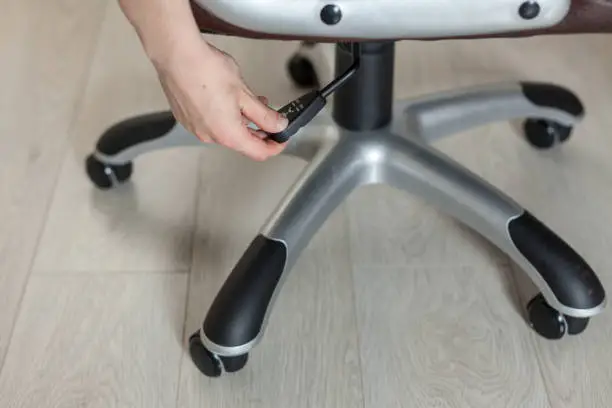 Photo of The girl adjusts the height of the new brown office chair