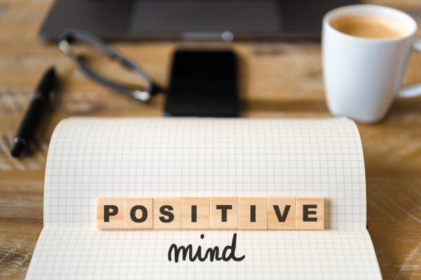istock Closeup on notebook over wood table background, focus on wooden blocks with letters making Positive Mind text 970816154