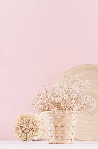 istock Gentle spring vanilla background with white dry flowers and bamboo dish on light table and pink wall. 970819428