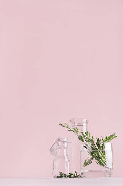 istock Modern simple art pink home decor with green plant in transparent vases on soft light white wood table, vertical. 970820082