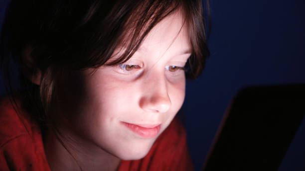 istock Caucasian girl in bed playing tablet in internet in dark blue light under blacket. 970826770