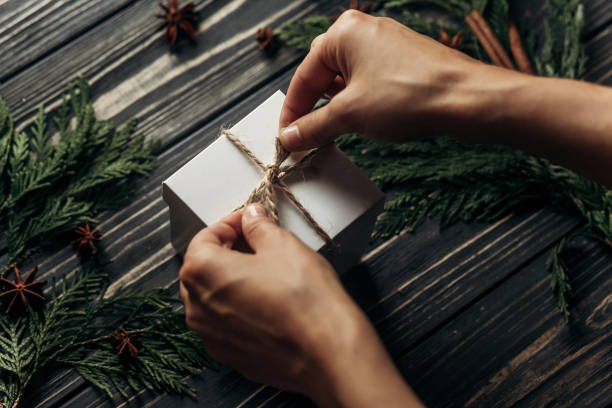istock hands wrapping christmas simple present tying bow on stylish rustic wooden background with space for text. greeting card concept. seasonal greetings for winter holidays 970829500