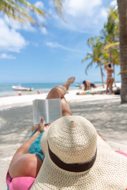 istock Woman relaxing and reading on tropical beach 970832524