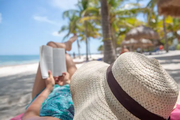 Woman relaxing and reading on tropical beach, Caribbean Mexico