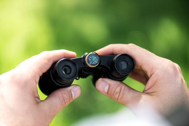 istock cropped shot of man holding binoculars on blurred green background 970843980