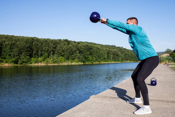istock Young man exercise with kettlebell by the lake 970844144