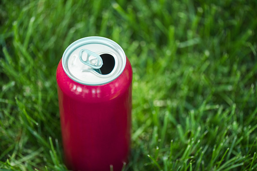 close up view of soda in pink can on green lawn