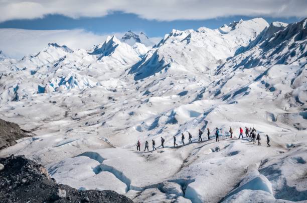 A line of tourists trekking on glacier at the Perito Moreno Glacier, El Calafate, Patagonia, Argentina, on a sunny but cloudy day. Perito Moreno Glacier is one of the largest glaciers in the Patagonian ice field. In addition to its accessibility, it is also one of the few glaciers in the world that are actively advancing. The glacier begins at the Andes Mountains bordering Argentina and Chile. santa cruz province argentina photos stock pictures, royalty-free photos & images
