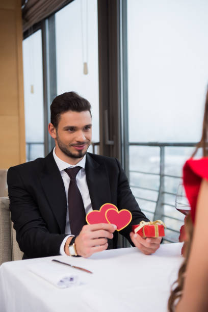 istock partial view of young man presenting gift to girlfriend on romantic date in restaurant 970860896