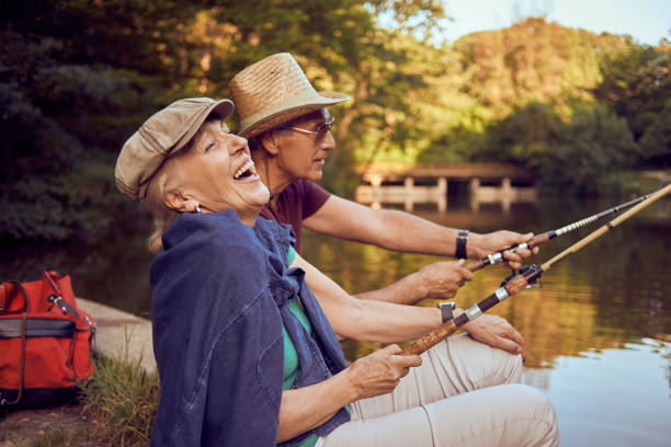 beautiful senior couple enjoying on the lake fishing and having fun stock photo
