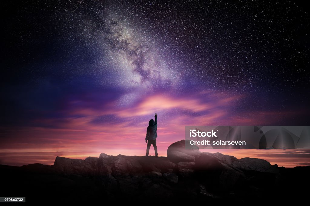 Night Landscape And Milky Way Night time long exposure landscape photography. A man standing in a high place reaching up in wonder to the Milky Way galaxy, photo composite. Star - Space Stock Photo