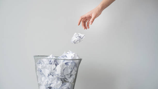 mujer mano lanzando arrugado papel en cesta - botar fotografías e imágenes de stock