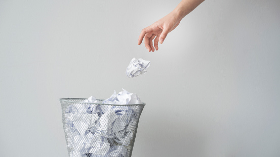 Woman hand throwing crumpled paper in basket