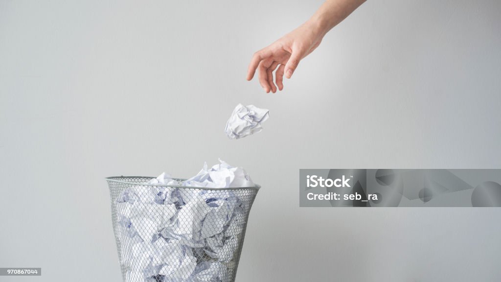 Woman hand throwing crumpled paper in basket Garbage Stock Photo
