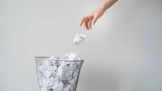 Photo of Woman hand throwing crumpled paper in basket