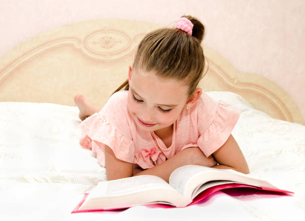 istock Adorable little girl child is reading a book 970867336