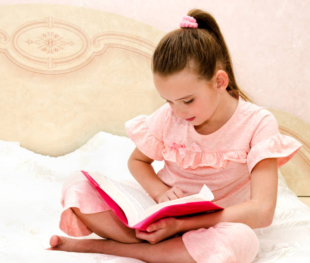 istock Adorable little girl child is reading a book 970867492