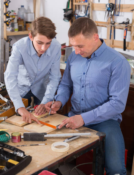 istock father and teen son working with wood plank in workshop 970868588