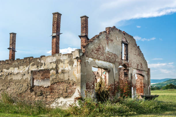 istock Destroyed old brick house without roof and with chimneys, broken windows, window frames, door and bricks 970871706