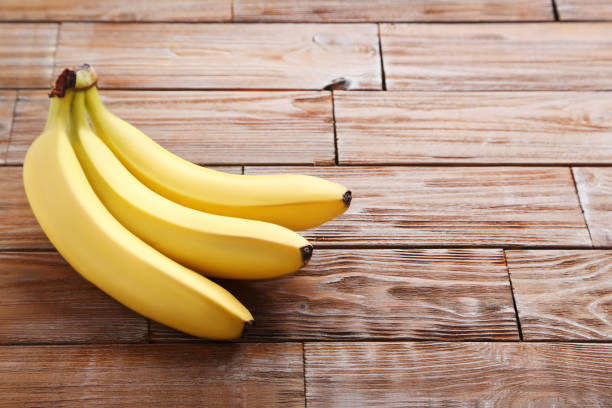 istock Sweet bananas on brown wooden table 970888224