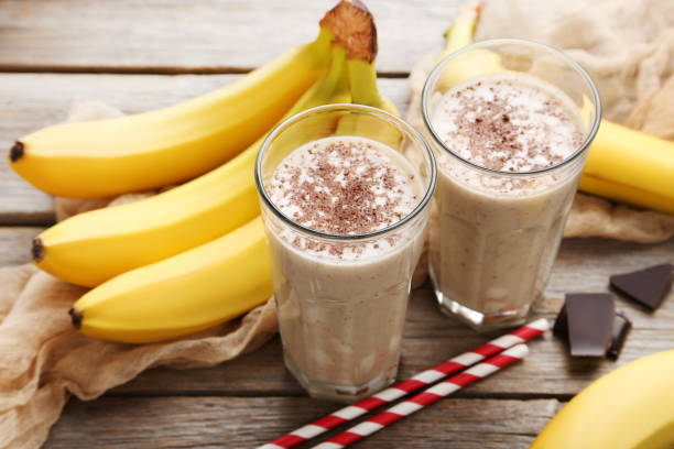 istock Cocktail with bananas in glasses on grey wooden table 970888374