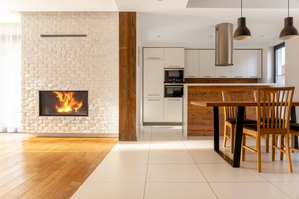 cheminée à l’intérieur spacieux de la maison blanche avec des chaises en bois à table près de cuisine. vraie photo - storey photos et images de collection