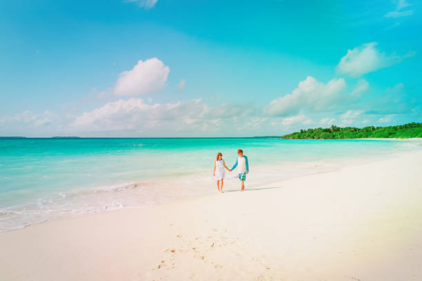 istock happy loving couple walking on beach 970899624